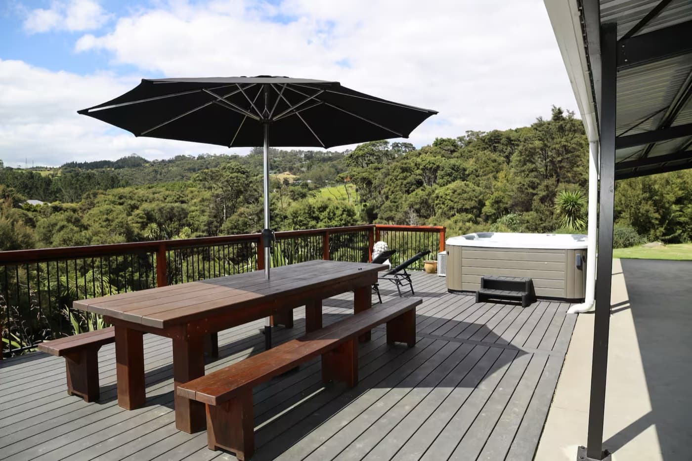 The lower deck with the long table, umbrella and spa pool