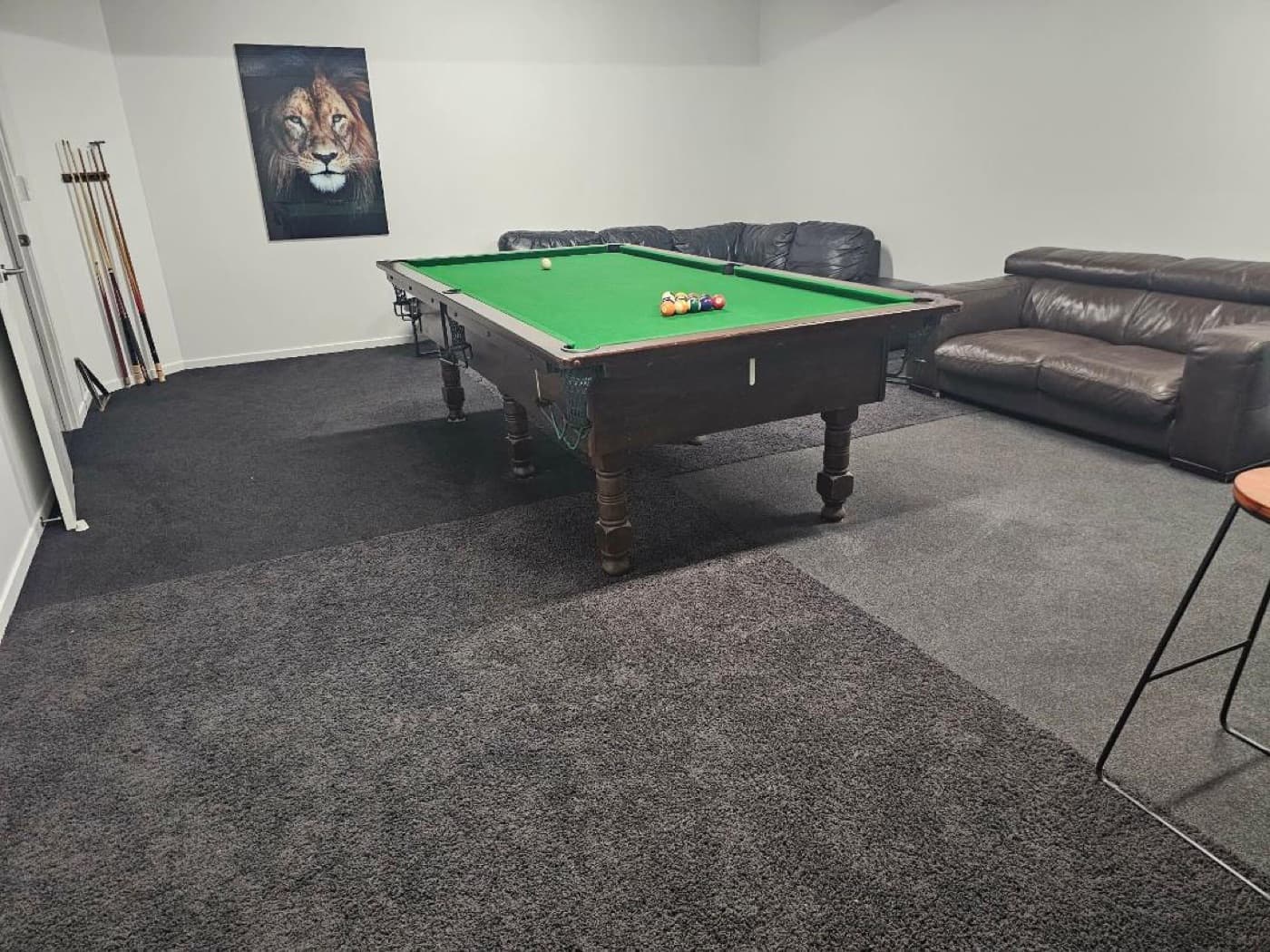 The pool table with the bar and stools behind