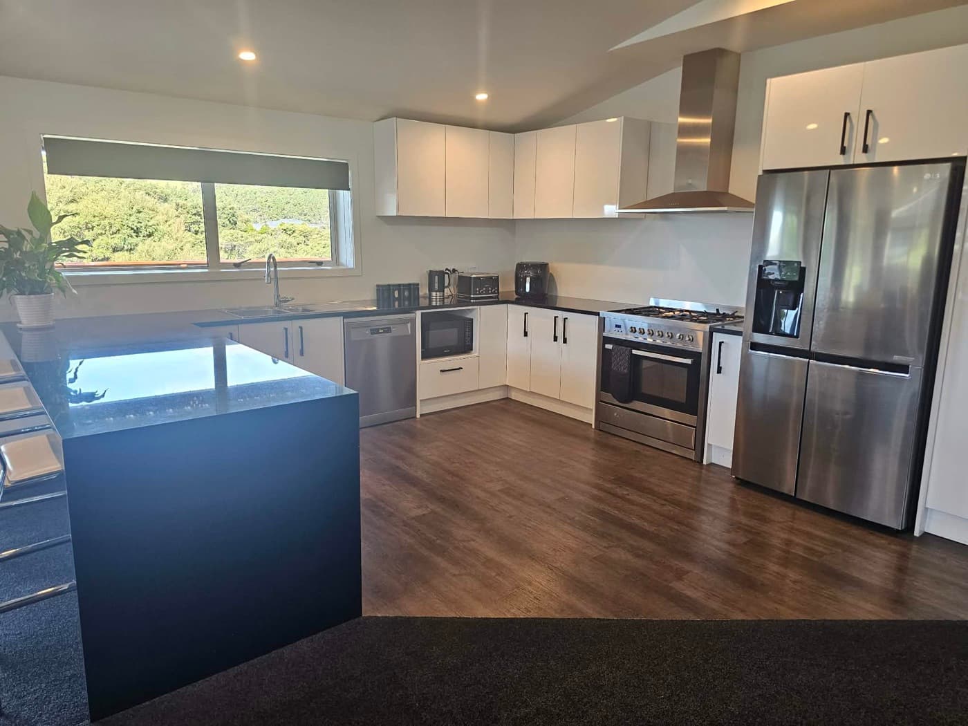 The full kitchen with island, gas hob, oven and large fridge
