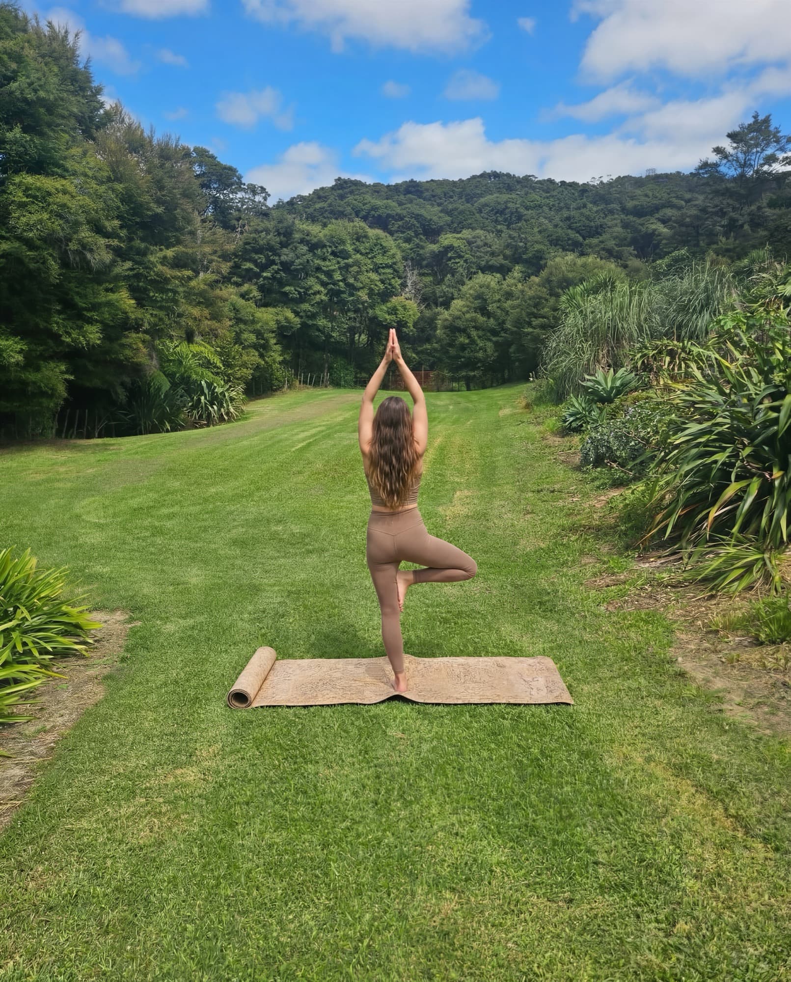 A guest practising yoga on the lawn, native bush beyond